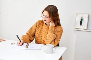 Woman sitting at a desk writing into a planner